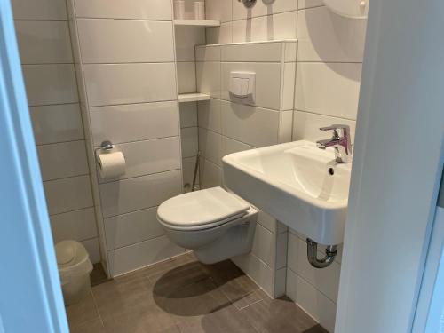 une salle de bains blanche avec toilettes et lavabo dans l'établissement Haus am Park Sünnig Utsicht, à Norderney