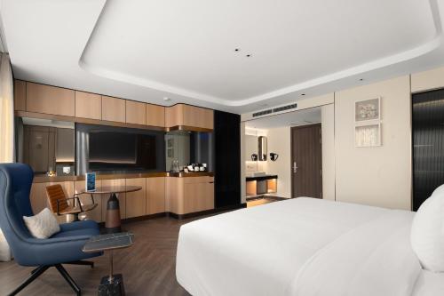 a bedroom with a large white bed and a blue chair at Grand Pioneers Halong Bay Cruise 1 in Ha Long
