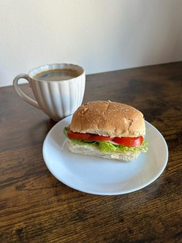 uma sandes num prato ao lado de uma chávena de café em Landvetter Airport B&B em Härryda