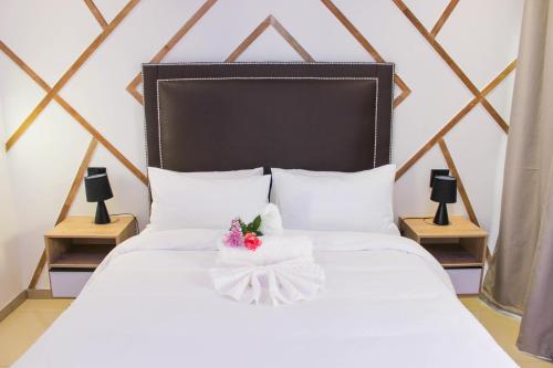 Deluxe Residence - Windhoek في ويندهوك: سرير أبيض مع اللوح الأمامي الأسود والأزهار عليه