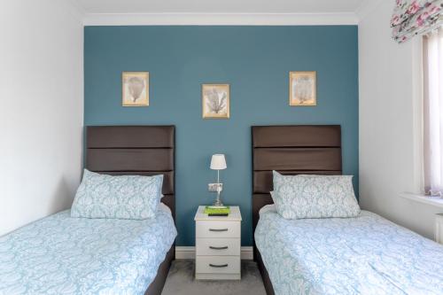 2 camas en un dormitorio con paredes azules en Room in Guest room - Apple House Wembley Twin Room, en Edgware