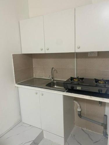 a white kitchen with a sink and a stove at Studio near Burj khalifa (emirates tower metro station) in Dubai