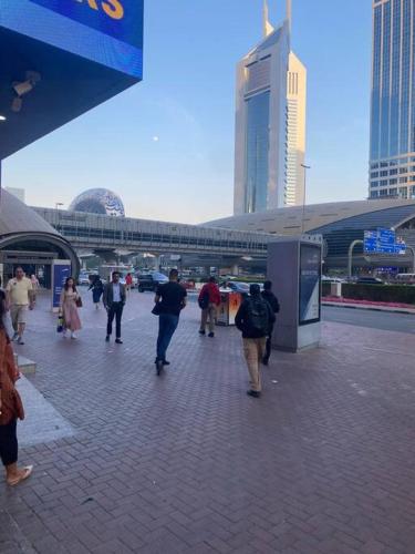 a group of people walking down a sidewalk in a city at Studio near Burj khalifa (emirates tower metro station) in Dubai