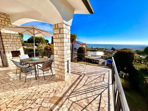 ヌマーナにあるVilla Edith - stupenda villa con terrazzo vista mare, giardino e spiaggia inclusaのパティオ(テーブル、傘付)