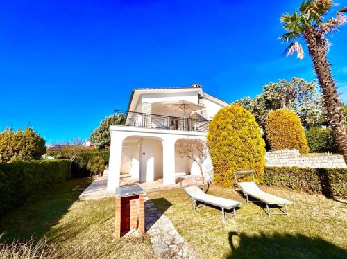 ヌマーナにあるVilla Edith - stupenda villa con terrazzo vista mare, giardino e spiaggia inclusaの椅子2脚とヤシの木のある家