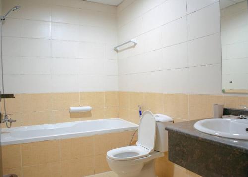 a bathroom with a toilet and a sink and a tub at Your Silicon Oasis Escape-1bhk in Dubai