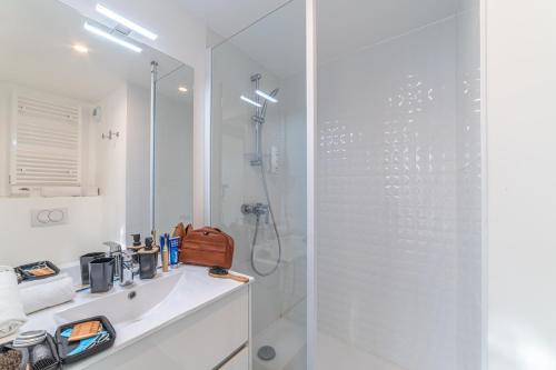 a white bathroom with a shower and a sink at Break & Home Clermont-Ferrand Les Carmes Dechaux in Clermont-Ferrand