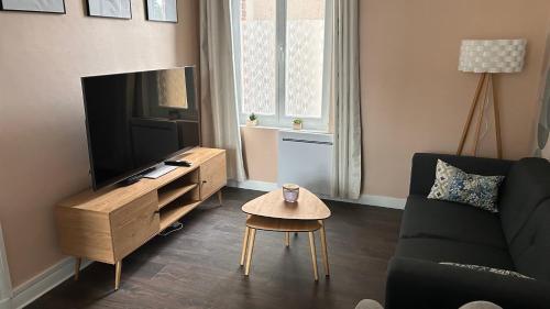 a living room with a couch and a tv and a table at L'appartement de Julie in Albert