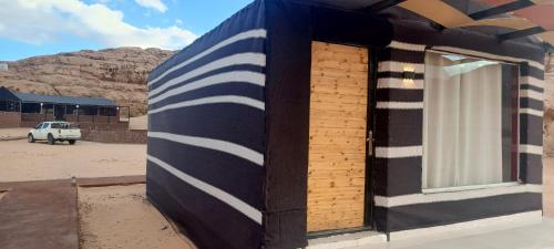 a building with a blue and white striped wall at Wadi Rum Calma camp in Aqaba