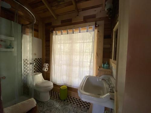 ein Badezimmer mit Waschbecken und Toilette und einem Fenster in der Unterkunft La Casita del Bosque in Castro