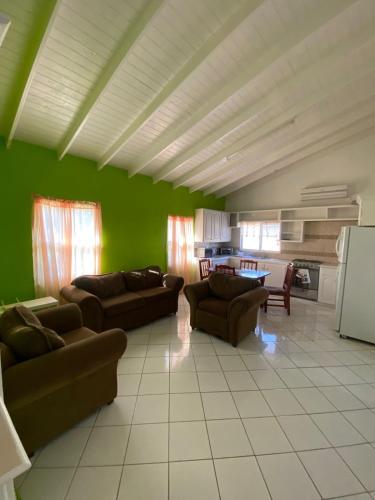 una sala de estar con 2 sofás y una pared verde en Thrillers Apartments en Gwa Kay