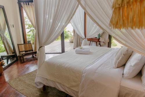 a bedroom with a white bed with curtains and a porch at Mantaray Siargao in General Luna