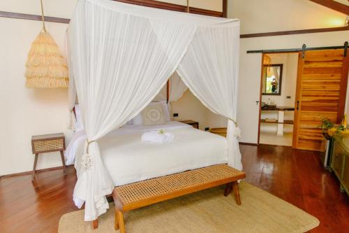 a bedroom with a white bed with a canopy at Mantaray Siargao in General Luna