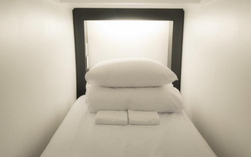 a stack of white pillows sitting on top of a bed at CANVAS BLACK Guesthouse in Busan