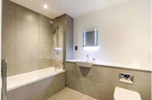 y baño con bañera, lavamanos y ducha. en Impeccable 1-Bed Apartment in London en Londres