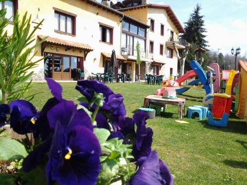 a yard with a playground with purple flowers at Apartamentos Els Ocells in Camprodon