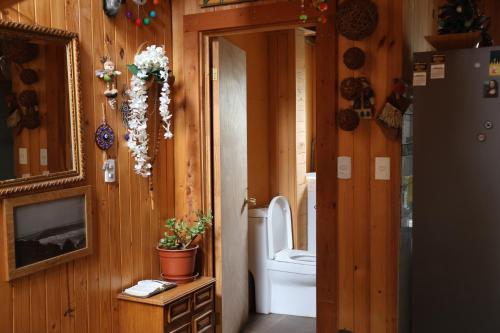 Habitación con paredes de madera y baño con aseo. en Casa infiernillo en Pichilemu