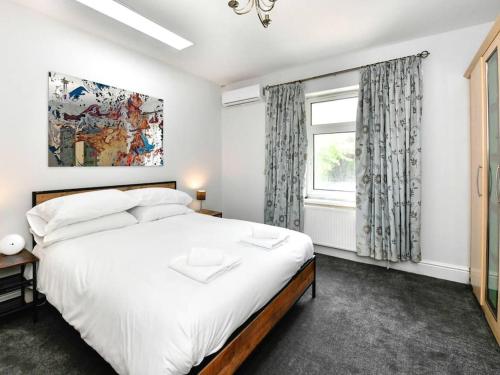 - une chambre avec un grand lit blanc et une fenêtre dans l'établissement Entire 5 Bedroom House & Parking, à Cardiff