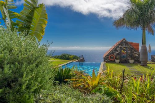 a resort with a swimming pool and the ocean in the background at Casas Da Vereda in Estreito da Calheta