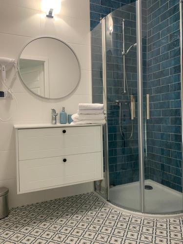 Un baño con lavabo y ducha con espejo. en Apartament Hamptons Perłowa Przystań, en Sianożęty