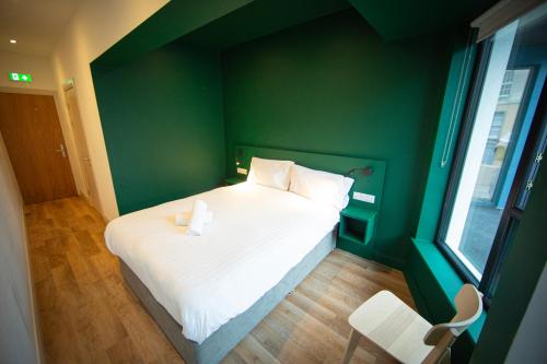 een bed in een kamer met een groene muur bij Heyday Hostel Ballina in Ballina