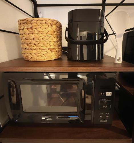 a black microwave sitting on a shelf next to a coffee maker at 枕木 New house with Huge View for Family-Group in Tokyo