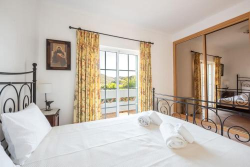 - une chambre avec un lit blanc et une grande fenêtre dans l'établissement Moradia T3 Com Terraço Solarengo, à Carrapateira