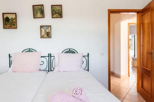 a bedroom with a bed with pink slippers on it at Moradia T3 Com Terraço Solarengo in Carrapateira