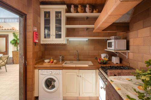 a kitchen with a washing machine and a sink at Villa Areal Porto Santo - By An Island Apart in Porto Santo