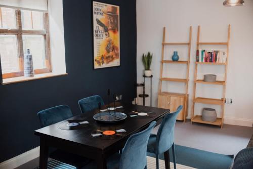 a dining room with a black table and blue chairs at Grade II Listed Flint Cottage Sleeps 4 in Norwich