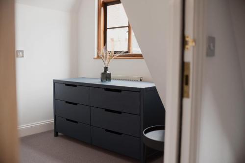 a bathroom with a dresser and a window at Grade II Listed Flint Cottage Sleeps 4 in Norwich