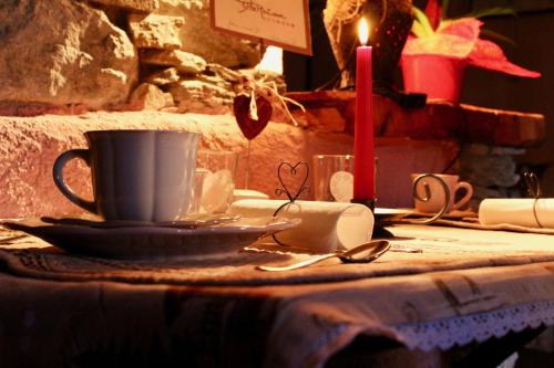 a table with a coffee cup and a candle at CleMaison Antica Dimora Apartments CIR VDA GIGNOD 0013 in Gignod