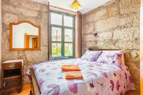 - une chambre avec un lit et un mur en pierre dans l'établissement House CONTU1000, à Porto
