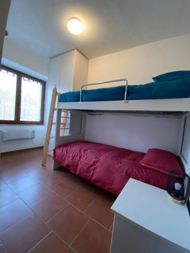 Zimmer mit 2 Etagenbetten und einem roten Sofa in der Unterkunft Perla alpina in Abetone