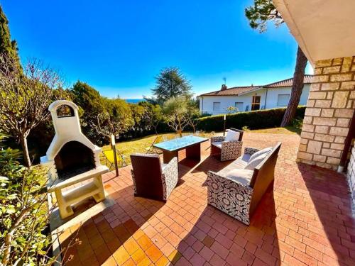 a patio with a table and chairs and a fireplace at Villa Renata, bellissima villa con terrazzo vista mare e spiaggia inclusa in Numana