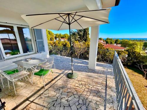 a patio with an umbrella and a table and chairs at Villa Renata, bellissima villa con terrazzo vista mare e spiaggia inclusa in Numana