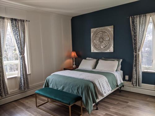 a bedroom with blue walls and a bed and a chair at Maison Zacharie in Desbiens