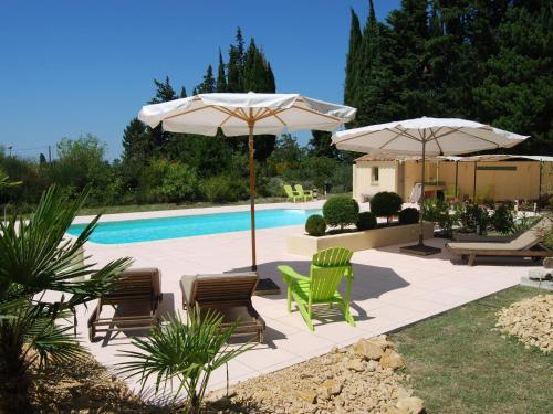 un patio con sillas y sombrillas y una piscina en Beautiful appartment with pool in Provence en Valréas