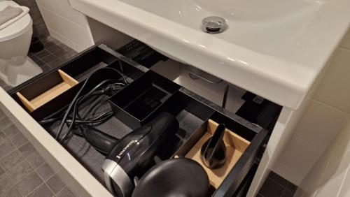 a drawer under a bathroom sink with a utensils at Cozy Apartment near Aura river in Turku