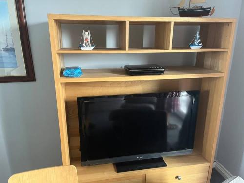 a wooden entertainment center with a television in it at Anchors Away by the Sea in Harwich