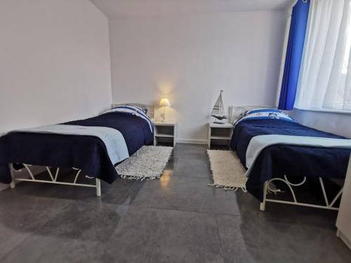 two beds in a room with blue comforters at Plażowa 2 in Rowy