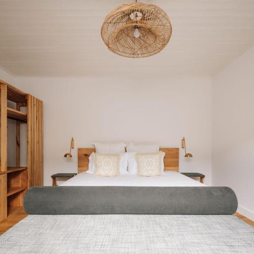 a bedroom with a large bed with white sheets and pillows at Adega do Fogo in São Roque do Pico