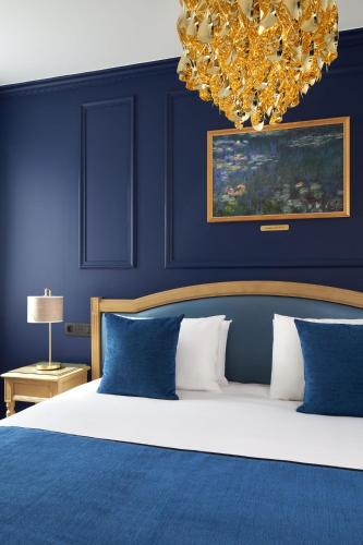 a bedroom with a bed with blue walls and a chandelier at Hotel Villa Romantic & Spa in Paris