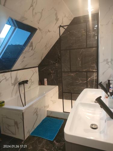 La salle de bains est pourvue d'une baignoire blanche, d'un lavabo et d'une fenêtre. dans l'établissement Villa du Littoral, à Mers-les-Bains