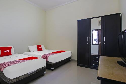 ein Schlafzimmer mit 2 Betten, einem Kleiderschrank und einem TV in der Unterkunft Super OYO 92437 Wahidin Guesthouse in Pekalongan