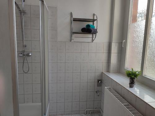 a white tiled bathroom with a shower and a window at Ferienwohnung Holly by Bad Frankenhausen in Rottleben