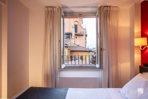 a bedroom with a window with a view of a building at Urbanicooh Asinelli - Piazza Maggiore View in Bologna