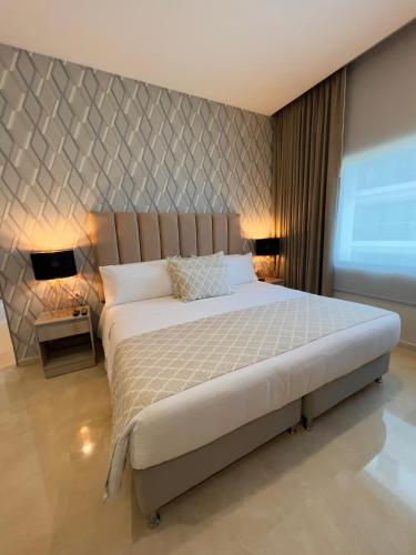 a bedroom with a large bed and two lamps at Hotel Dorado Plaza Alto Prado in Barranquilla