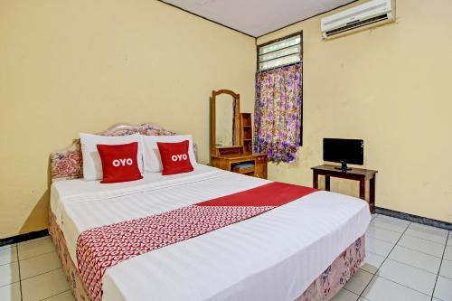 een slaapkamer met een groot bed met rode kussens bij OYO 92761 Hotel Sendang Asri in Wonogiri