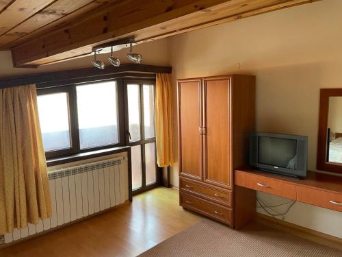 a living room with a tv and a large window at Kalaidjievi in Bansko